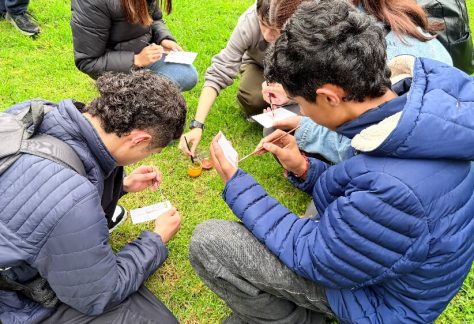 Un grupo de jóvenes trabajando en el suelo sobre sus dibujo