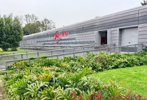Vista exterior de las instalaciones del Metro de Bogotá con jardines en primer plano.