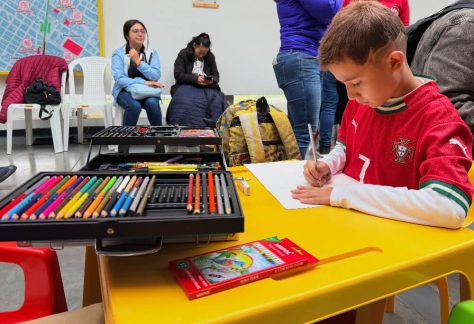 Un niño con camiseta roja trabaja concentrado con colores