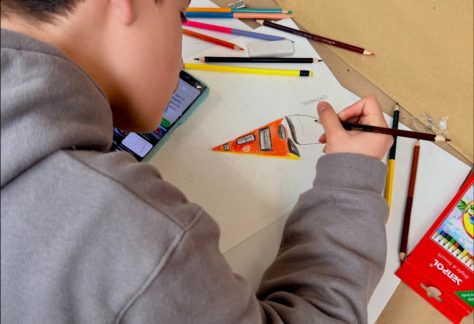 Niño dibuja con detalle sobre una hoja en blanco.