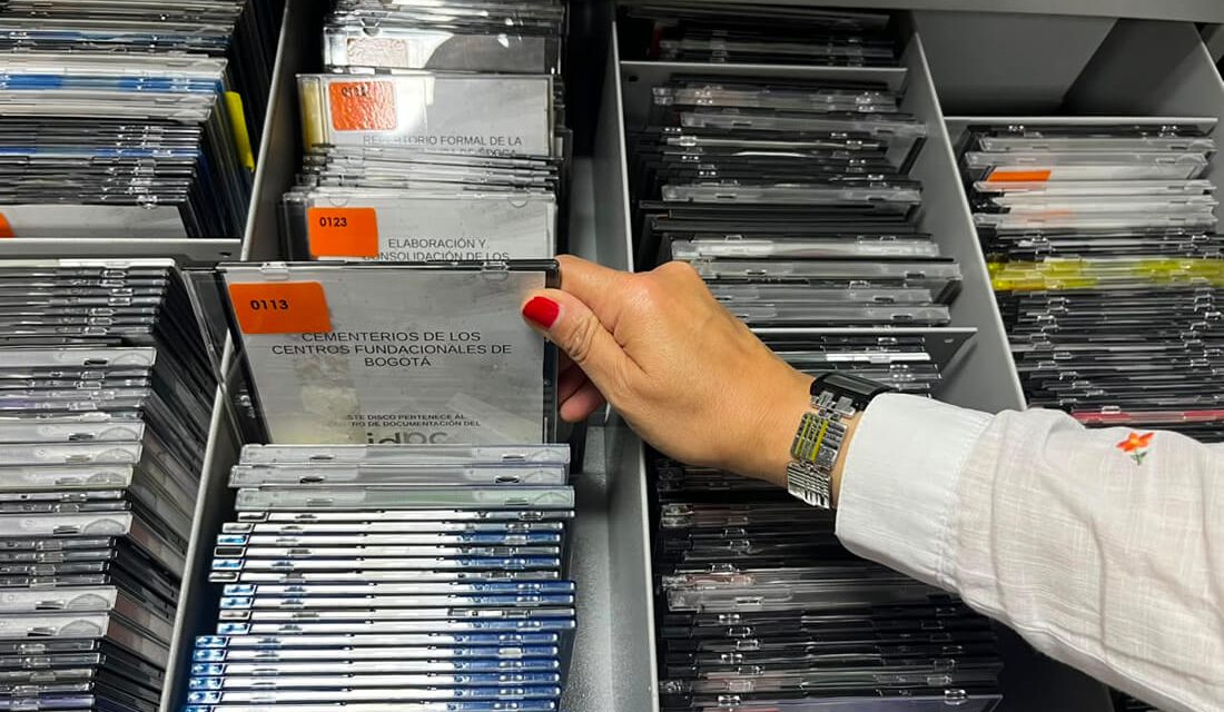 Primer plano de la mano de una persona consultando y clasificando documentos organizados en un archivador del Centro de Documentación.