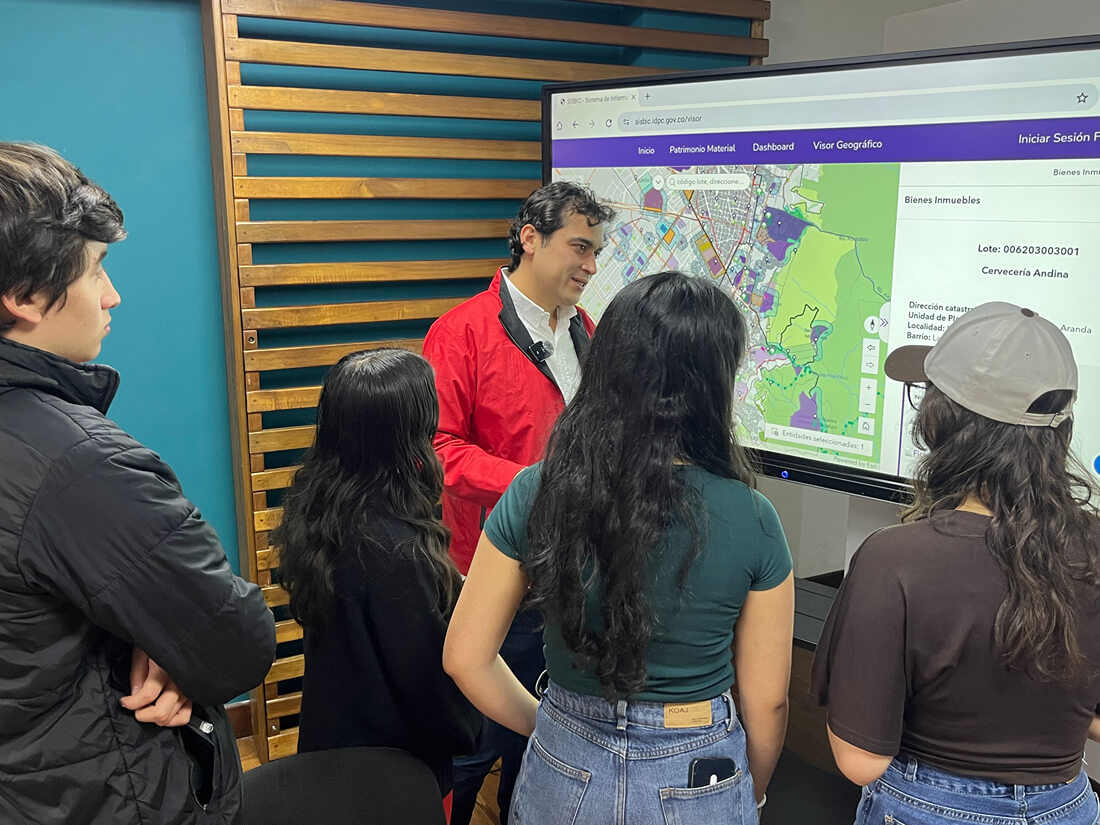 Grupo de personas analiza el visor geográfico interactivo de bienes inmuebles patrimoniales de Bogotá junto al director del IDPC durante una jornada de planeación.