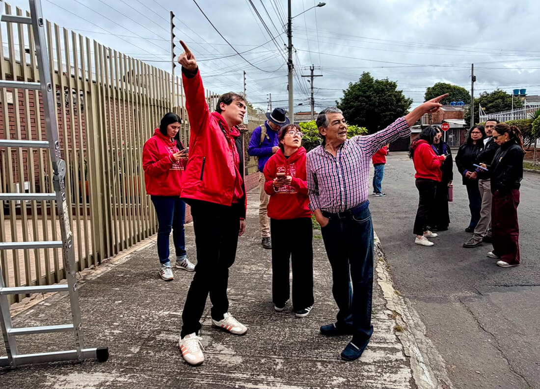 Integrantes del IDPC y ciudadanos señalan y evalúan la estructura alta de una edificación durante un recorrido técnico de patrimonio en Bogotá.