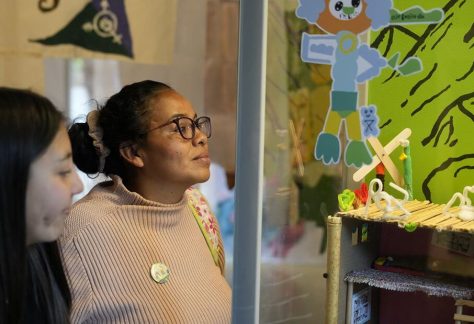 Dos mujeres adultas ven sonrientes las exposiciones.