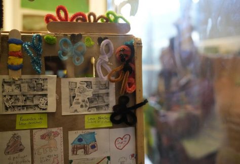 Toma en detalle que muestra de cerca el interior de una de las vitrinas con dibujos infantiles, personajes recortados y decoraciones de corazones fijadas en el mostrador.