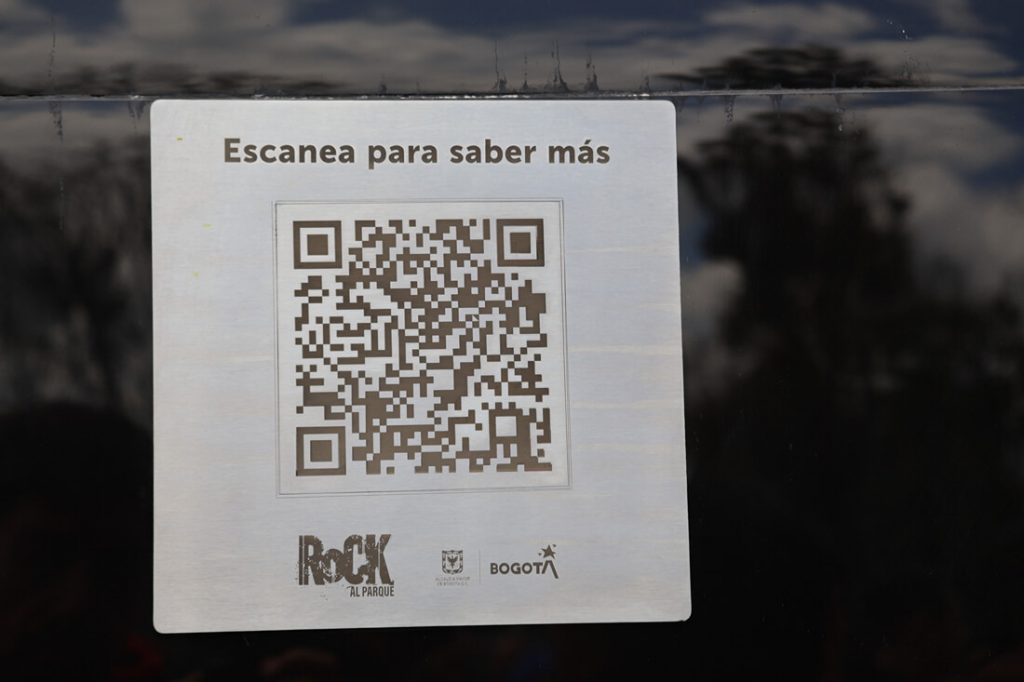 Placa con código QR y texto 'Escanea para saber más', logos de Rock al Parque y Bogotá.