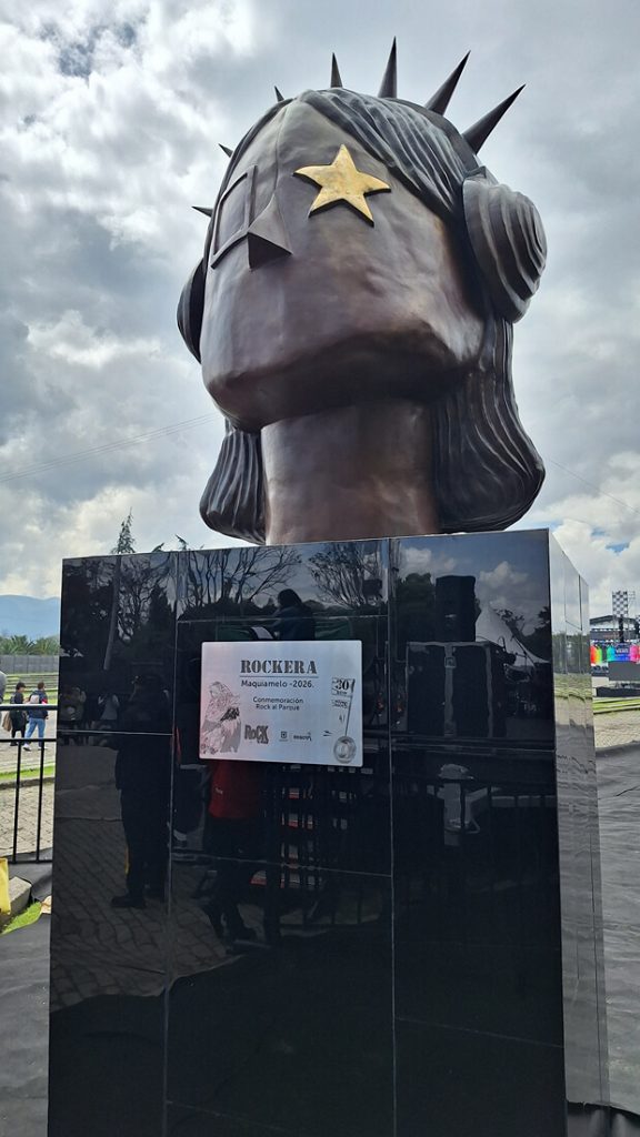 Busto de bronce de la escultura 'La Rockera' con audífonos de púas y estrella en el ojo.