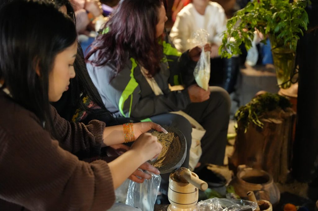 Mujer en primer plano participando en una actividad comunitaria junto a un recipiente con una preparación tradicional.