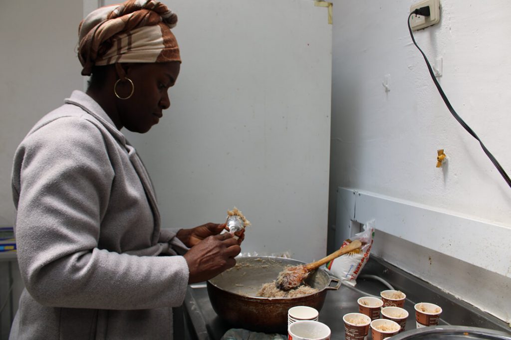 Mujer palenquera con pañoleta en la cabeza cocinando en una olla sobre un fogón.