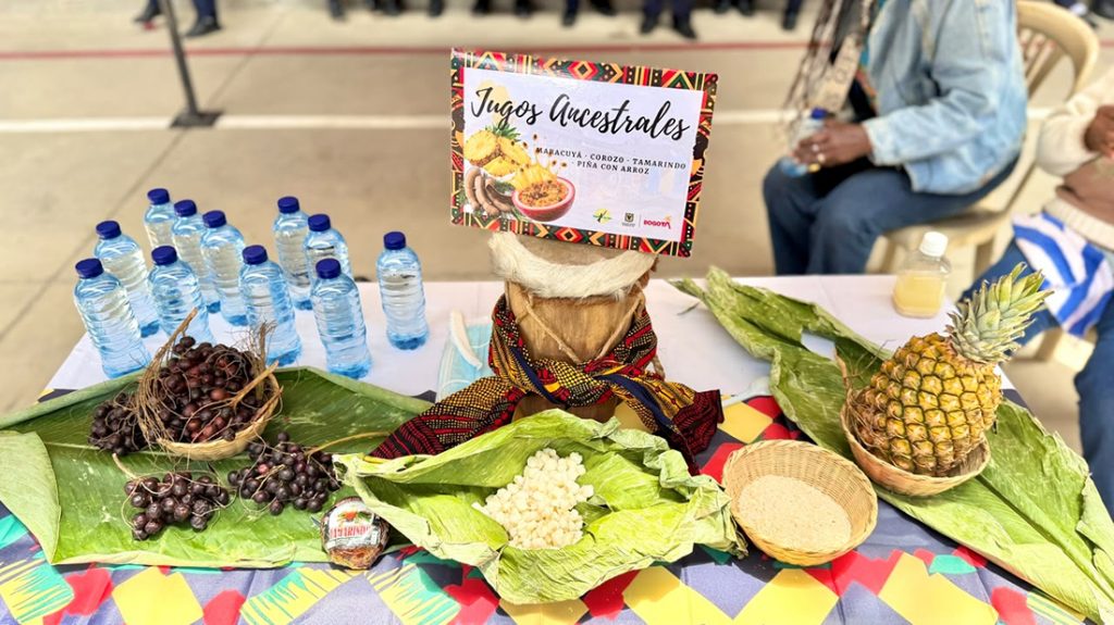 Mesa con una muestra de productos ancestrales, frascos con bebidas y un letrero que dice "Jugos Ancestrales".