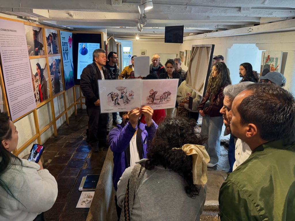 Expositores muestran una ilustración histórica impresa a los asistentes durante una charla del IDPC en una sala de exposición.