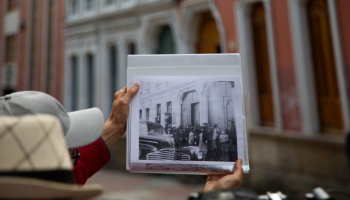Hombre sosteniendo foto antigua del centro histórico durante recorrido