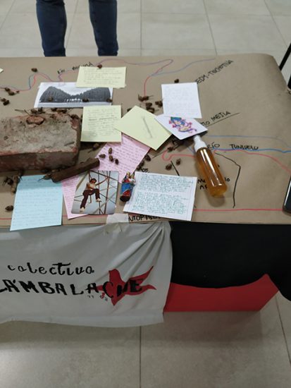 Objetos y artefactos compartidos por los participantes sobre un plano:notas, fotografías, una virgen, un ladrillo, semillas y agua en un spray.